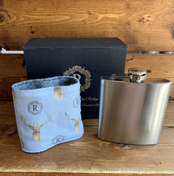 Personalised 6oz stainless steel hip flask which comes with a removable Harris Tweed sleeve.  The sleeve is fully lined in a bespoke stag fabric.  The Harris tweed sleeve can be embroidered with your choice of wording/name (up to 10 characters).