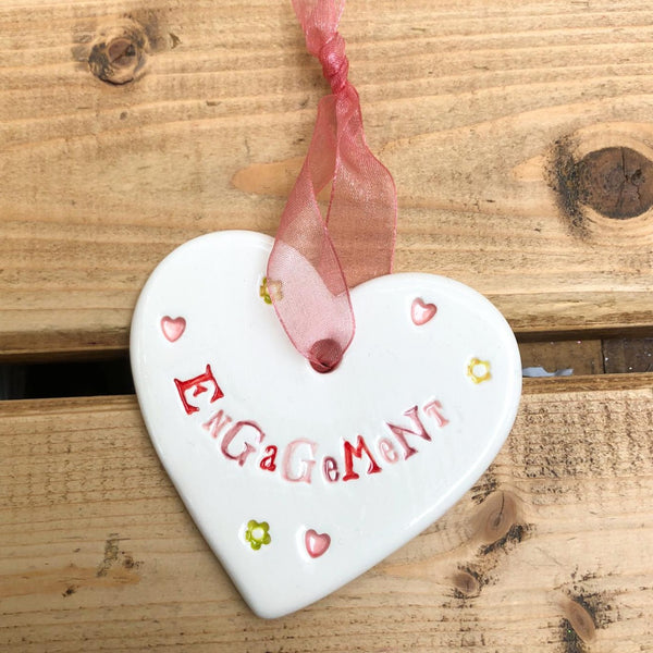 Hand painted ceramic heart featuring hearts and flowers design and the sentiment 'Engagement'  Handmade in the UK using clay, glaze and paint sourced locally.