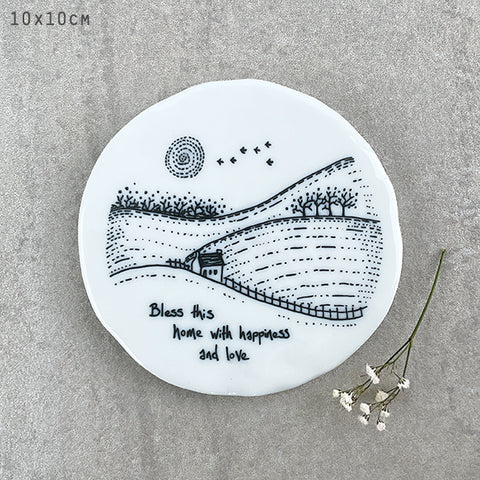 White porcelain East Of India coaster with traditional illustration saying Bless This Home