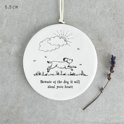 White porcelain round hanging decoration with dog illustration and black text reads ' beware of the dog it will steal your heart'