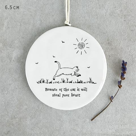 White porcelain round hanging decoration with cat illustration and black text which reads 'Beware of the cat, it will steal your heart'
