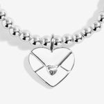 Silver plated 'Sending Love' stretch beaded Joma jewellery bracelet with hanging heart envelope charm on foil stamped sentiment card.