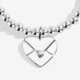 Silver plated 'Sending Love' stretch beaded Joma jewellery bracelet with hanging heart envelope charm on foil stamped sentiment card.