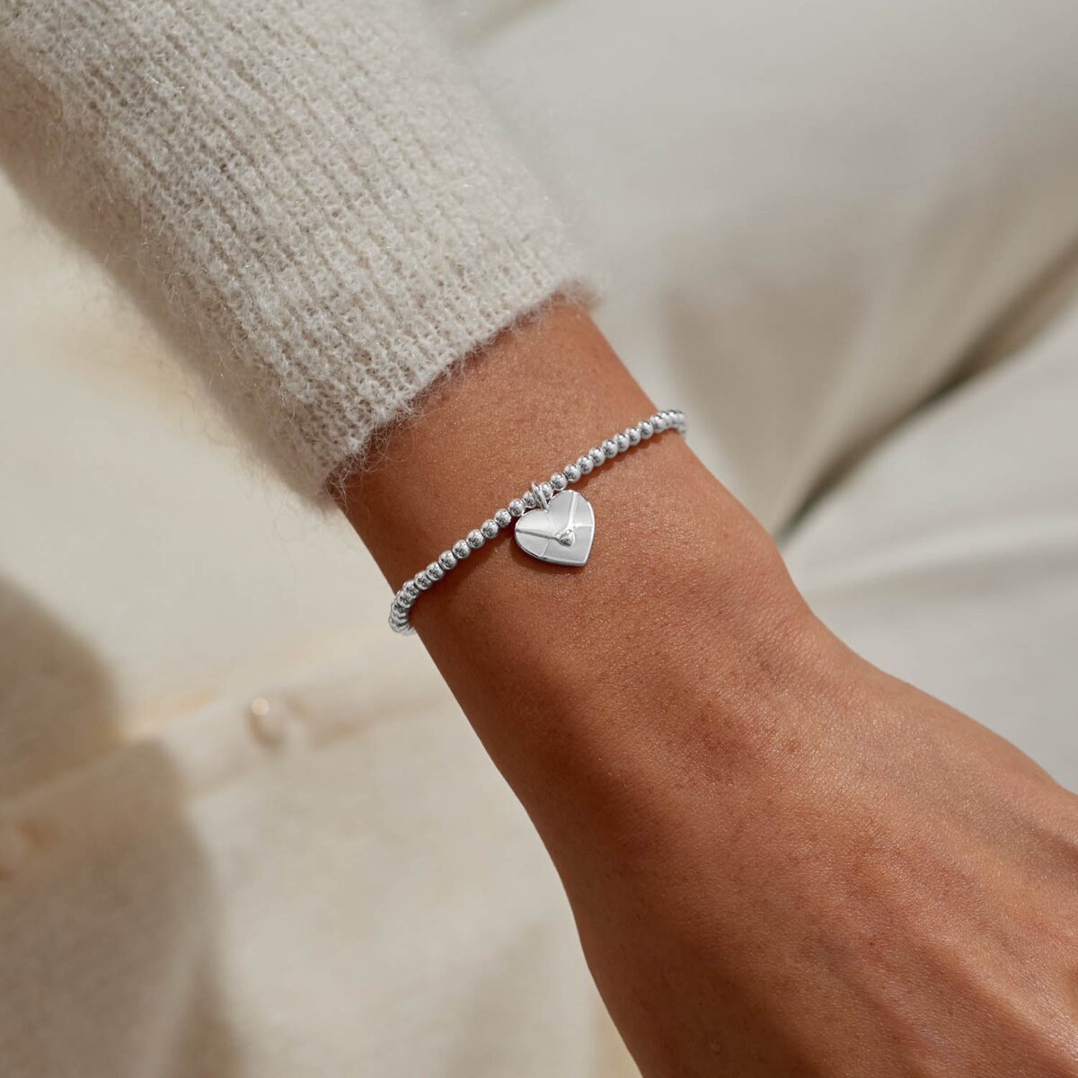 Silver plated 'Sending Love' stretch beaded Joma jewellery bracelet with hanging heart envelope charm on foil stamped sentiment card.