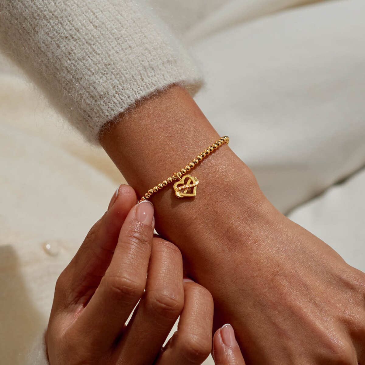 Gold plated Joma Jewellery bracelet with open heart hanging charm with infinity symbol and sparkle detail. Presented on a foil stamped sentiment card.