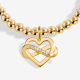 Gold plated Joma Jewellery bracelet with open heart hanging charm with infinity symbol and sparkle detail. Presented on a foil stamped sentiment card.