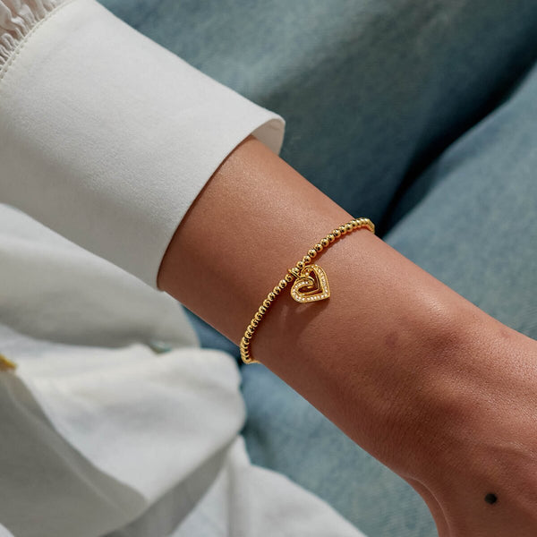 Gold plated Joma Jewellery bracelet for a friend with an open heart hanging charm with sparkle detail. Presented on a foil stamped sentiment card.