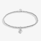a silver beaded bracelet with a silver charm of a dog sitting on a heart against a white background