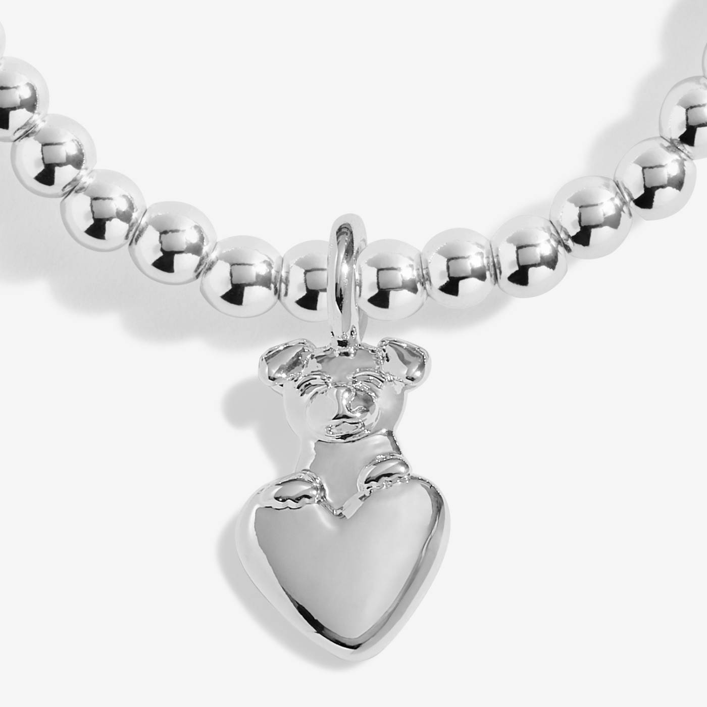 close up of a silver charm with a dog sitting on a heart
