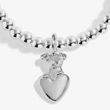 close up of a silver charm with a dog sitting on a heart
