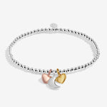 Silver plated beaded stretch Joma Jewellery bracelet with trio of charms - silver moon, gold and rose gold hearts. Presented on a sentiment card ready for gifting.