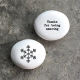 White porcelain pebble with black wording 'Thanks For Being Amazing' on one side and snow flake design on opposite side.