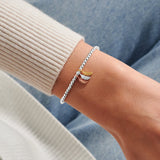 Joma jewellery stretch beaded bracelet with three hanging feather charms in silver, gold and rose gold plating presented on a foil stamped sentiment card.