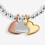 Joma jewellery stretch beaded bracelet with three solid hanging heart charms in silver, gold and rose gold plating presented on a foil stamped sentiment card.