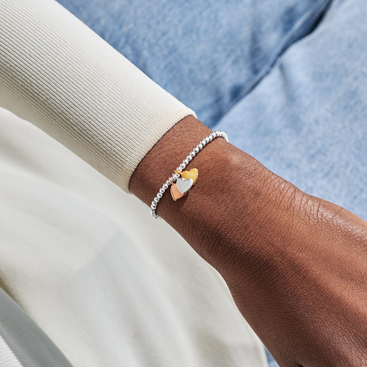 Joma jewellery stretch beaded bracelet with three solid hanging heart charms in silver, gold and rose gold plating presented on a foil stamped sentiment card.