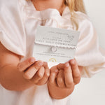 Silver plated girls Joma stretch bracelet with hanging heart charm presented on gifting card for Holy Communion