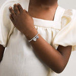 Silver plated girls Joma stretch bracelet with hanging heart charm presented on gifting card for Holy Communion