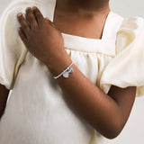 Silver plated girls Joma stretch bracelet with hanging heart charm presented on gifting card for Holy Communion