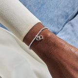 Woman wearing Joma Jewellery bracelet with interlocking heart charm