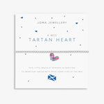 A Joma Jewellery 'A Wee Tartan Heart' bracelet on a white display card. The bracelet features a silver-toned chain and a small heart charm decorated with a pink, green, and purple tartan pattern.