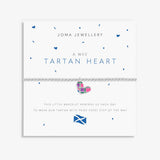 A Joma Jewellery 'A Wee Tartan Heart' bracelet on a white display card. The bracelet features a silver-toned chain and a small heart charm decorated with a pink, green, and purple tartan pattern.