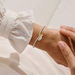 Bracelet with heart-shaped charms on a wrist against a neutral background