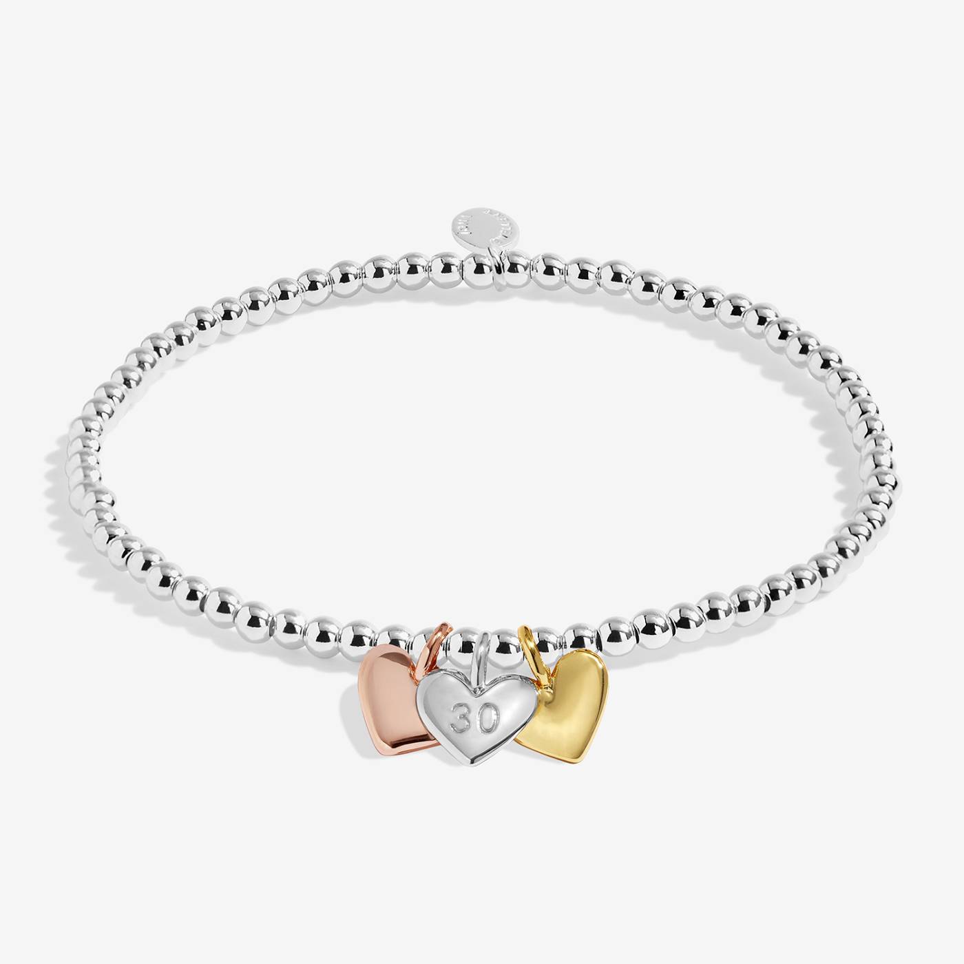 Silver bracelet with three heart-shaped charms on a white background