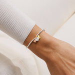 Bracelet with heart-shaped charms on a wrist against a neutral background