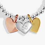 Bracelet with heart-shaped charms in silver, rose gold, and gold on a white background. Central heart is engraved with the number 50