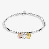 Silver bracelet with three heart-shaped charms on a white background