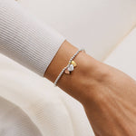 Bracelet with heart charms on a wrist against a neutral background