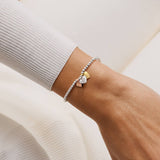 Bracelet with heart charms on a wrist against a neutral background