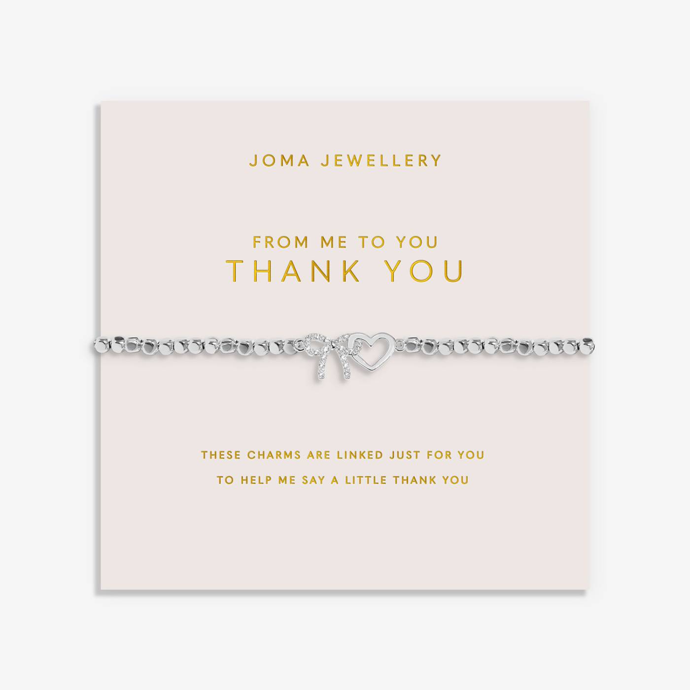 A silver beaded bracelet with heart charm and bow charm, presented on a pale pink card from Joma Jewellery that reads 'FROM ME TO YOU THANK YOU'.