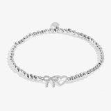 A silver beaded bracelet with a bow and open heart charm, embellished with small clear crystals, shown on a light grey background.