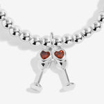 Joma Jewellery beaded stretch bracelet with hanging charm featuring 2 champagne glasses with red sparkle detail.