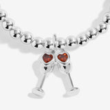 Joma Jewellery beaded stretch bracelet with hanging charm featuring 2 champagne glasses with red sparkle detail.