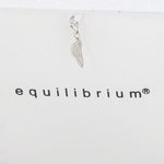 A silver wing-shaped pendant hanging from a white ribbon against a white background with the brand name 'equilibrium' printed below.