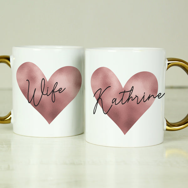 White mug with gold handle and pink heart design.  Can be personalised with a name and title eg Wife, Kathrine