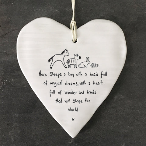 White Hanging Porcelain 'Wobbly' Round Heart baby gift from East of India which reads:  'Here sleeps a boy with a head full of magical dreams, a heart full of wonder and hands that will shape the world.'  The heart features an engraved illustration in East of India's unique style.  Material:  Porcelain