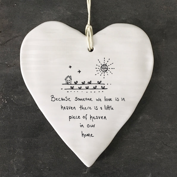 White Hanging Porcelain 'Wobbly' Round Heart from East of India which reads:  'Because someone we love is in heaven there is a little piece of heaven in our home.'  The heart features an engraved illustration in East of India's unique style.