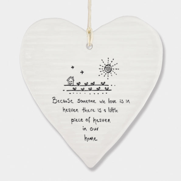 White Hanging Porcelain 'Wobbly' Round Heart from East of India which reads:  'Because someone we love is in heaven there is a little piece of heaven in our home.'  The heart features an engraved illustration in East of India's unique style.