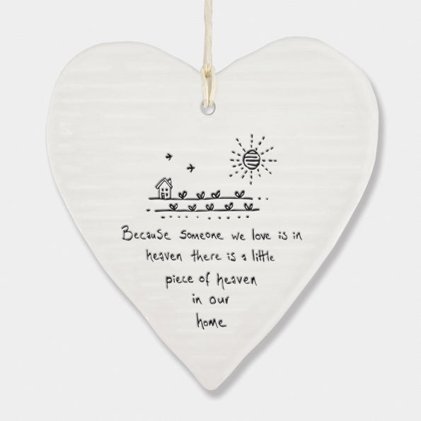 White Hanging Porcelain 'Wobbly' Round Heart from East of India which reads:  'Because someone we love is in heaven there is a little piece of heaven in our home.'  The heart features an engraved illustration in East of India's unique style.