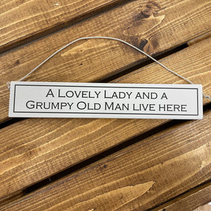 This wooden sign has to be the perfect gift for all couples who love a little humour.   Rustic hanging wooden sign - hand painted with the printed slogan:  'A lovely lady and a grumpy old man live here'  Handmade in the UK