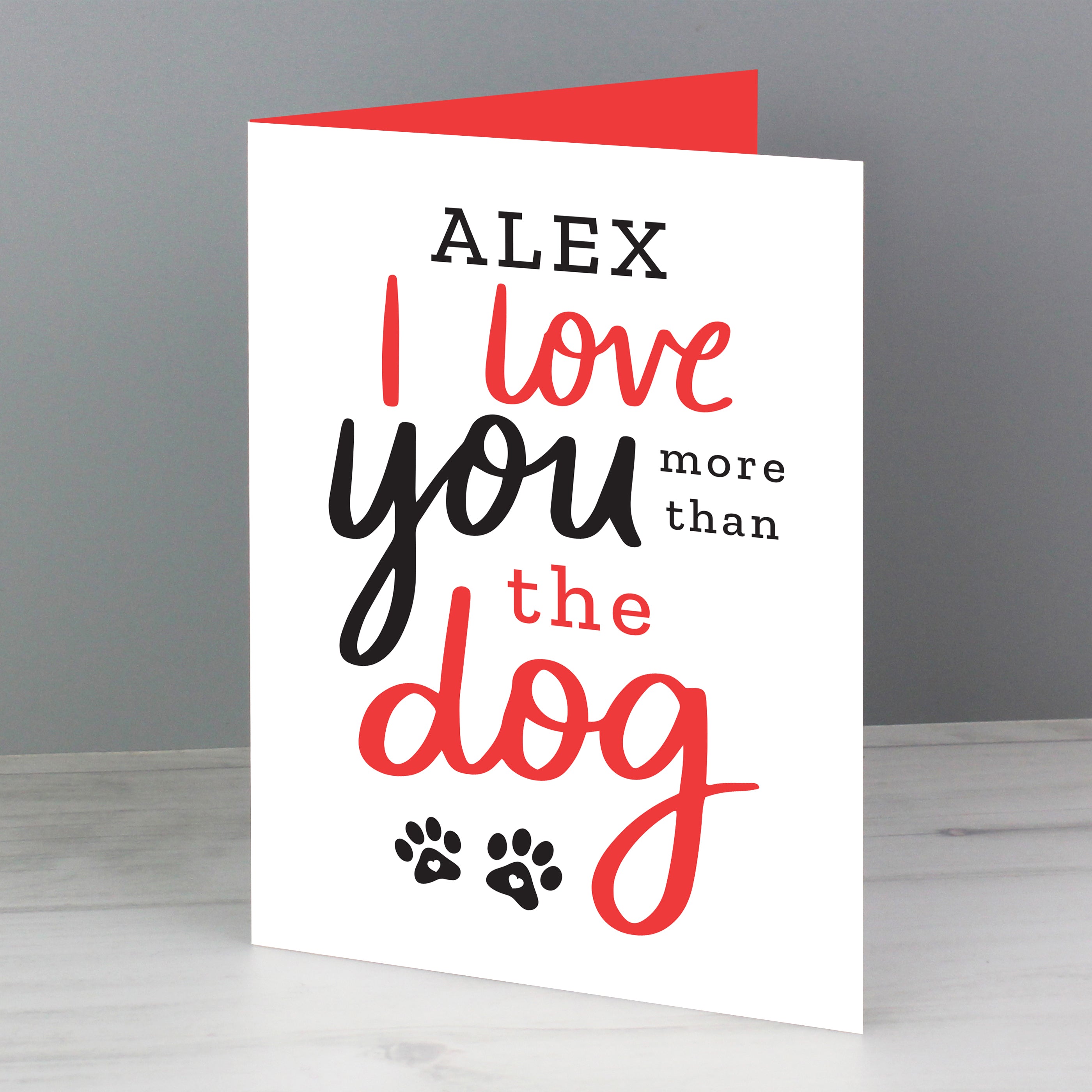 This personalised card features the wording 'I Love You More Than The Dog' and cute pawprint graphics 