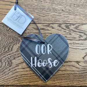 Hanging wooden heart on grey printed tartan with black ribbon and the sentiment:  'Oor Hoose'
