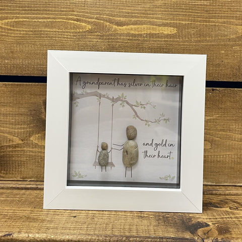 This gorgeous handmade pebble art picture from La de da Living with grandparent and child has the saying 'A grandparent has silver in their hair and gold in their heart'  Framed in a white, freestanding box frame this will make a perfect keepsake gift for a grandparent or grandparent to be.