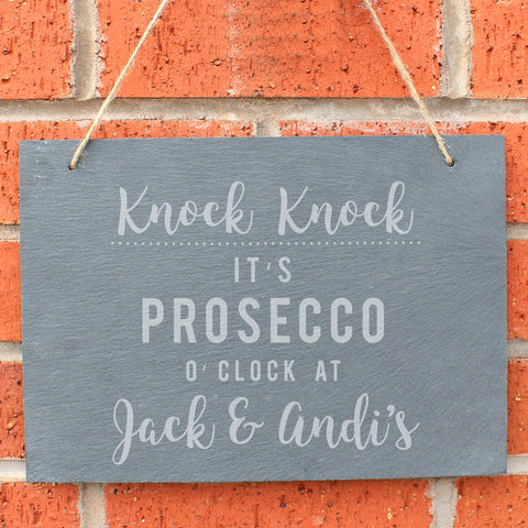 Slate hanging sign with natural, rustic string featuring the text:  'Knock Knock It's Prosecco o'clock at''  The sign can then be personalised with any name(s) up to 15 characte