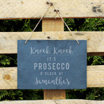 Slate hanging sign with natural, rustic string featuring the text:  'Knock Knock It's Prosecco o'clock at''  The sign can then be personalised with any name(s) up to 15 characte