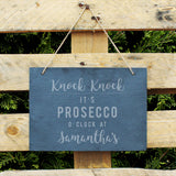 Slate hanging sign with natural, rustic string featuring the text:  'Knock Knock It's Prosecco o'clock at''  The sign can then be personalised with any name(s) up to 15 characte