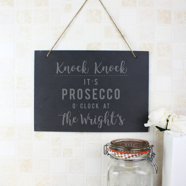 Slate hanging sign with natural, rustic string featuring the text:  'Knock Knock It's Prosecco o'clock at''  The sign can then be personalised with any name(s) up to 15 characte